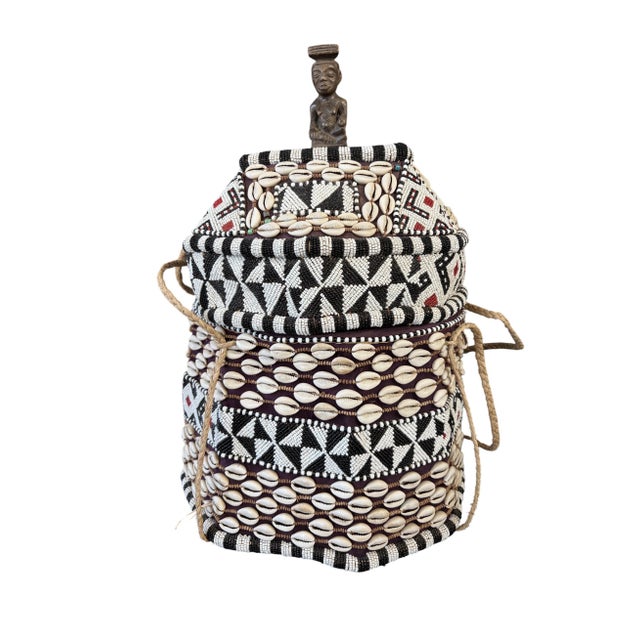 This vintage Kuba basket from the Democratic Republic of the Congo is handcrafted from raffia palm fibers and adorned with...