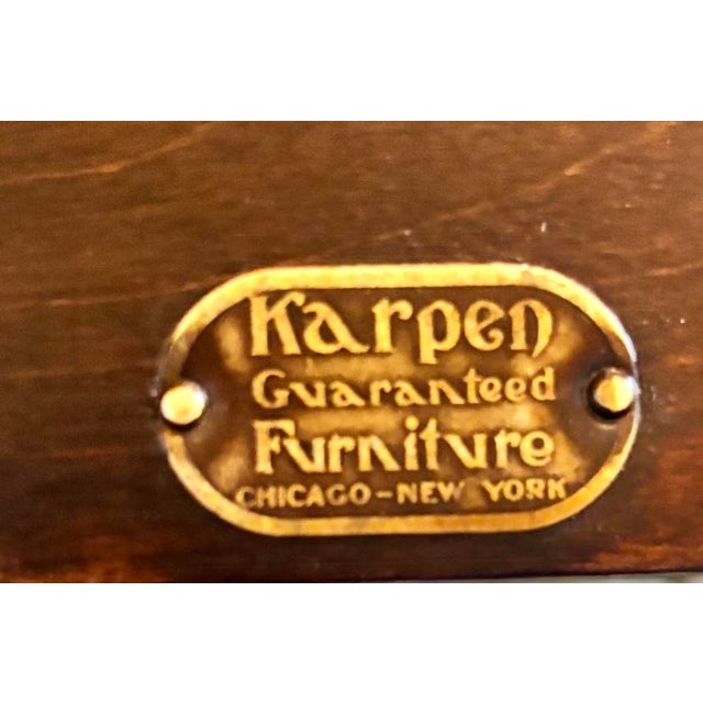 This antique lounge chair features a heavy wooden frame with ornate carvings, a caned back and sides, and floral tapestry...