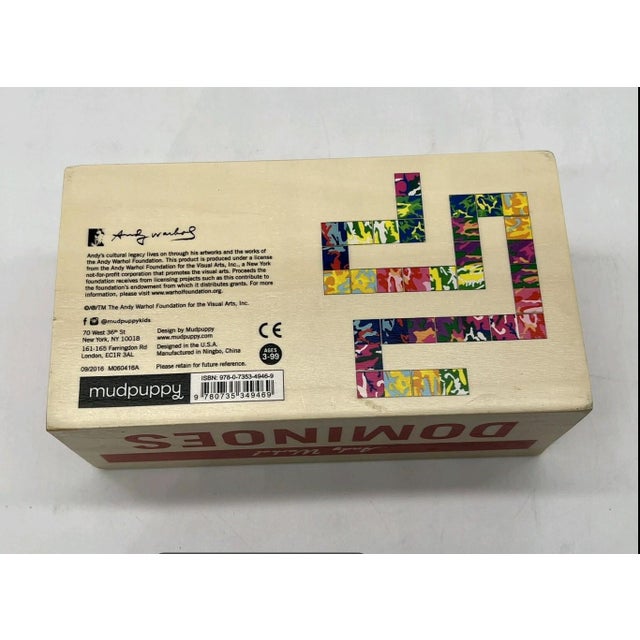 This wooden game box with sliding lid holds a 28 piece set of art dominos featuring Andy Warhol's iconic camouflage...