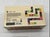 This wooden game box with sliding lid holds a 28 piece set of art dominos featuring Andy Warhol's iconic camouflage...