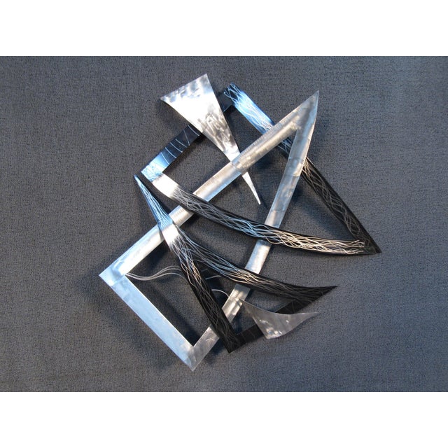 This vintage wall-mounted sculpture by Curtis Jere features geometric pieces of metal arranged in an abstract composition.
