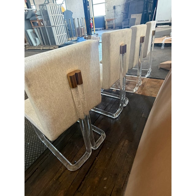 This set of four mid‑century dining chairs features striking lucite cantilever bases paired with tailored upholstered...