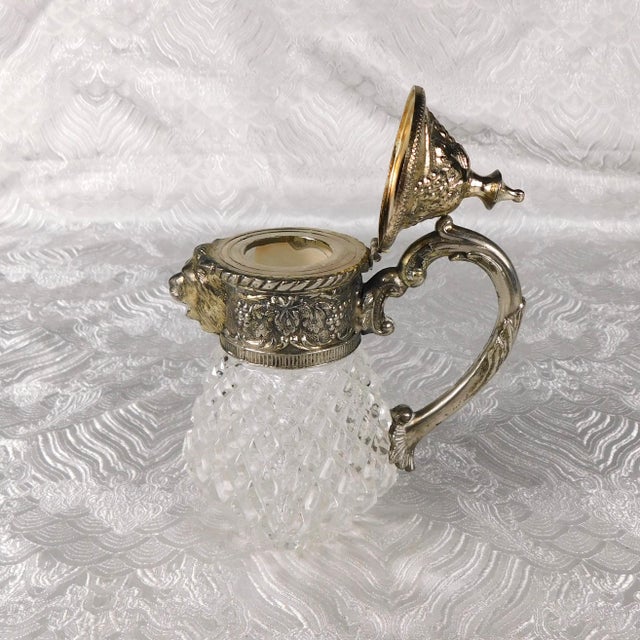 This is a, I think, a crystal pitcher (or milk jug, or creamer, or syrup pitcher) with a metal top that does not seem to...