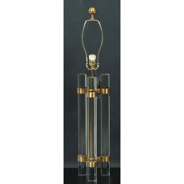 A modern John-Richard lamp. The lamp consists of 3 cylindrical lucite "wands" consolidated by 2 brass ring trios. A Fine...