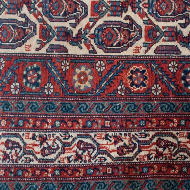An early 20th Century Persian Nahavand carpet with paisley motif field and multiple scrolling vine and floral borders....