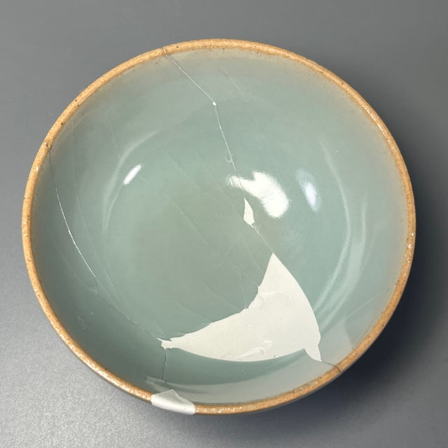 Classic Chinese celadon bowl with elegant rounded shape, finished in soft pale‑blue‑green glaze covered with fine natural...