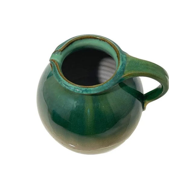 A Dutch earthenware jug, glazed in green, beige and brown colors. The jug is marked under the foot with the Mobach Utrecht...