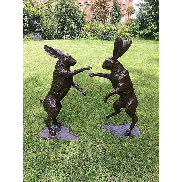 A wonderfully characterful and highly decorative pair of life-size bronze boxing hares, captured in animated fighting...