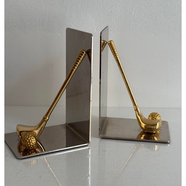 A pair of mid-century brass golf themed bookends featuring a club and ball with squared back. Please see condition details...