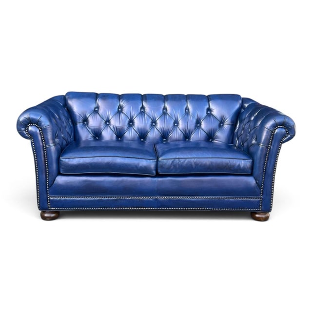 This vintage navy blue leather loveseat offers a refined interpretation of classic Chesterfield design, combining timeless...