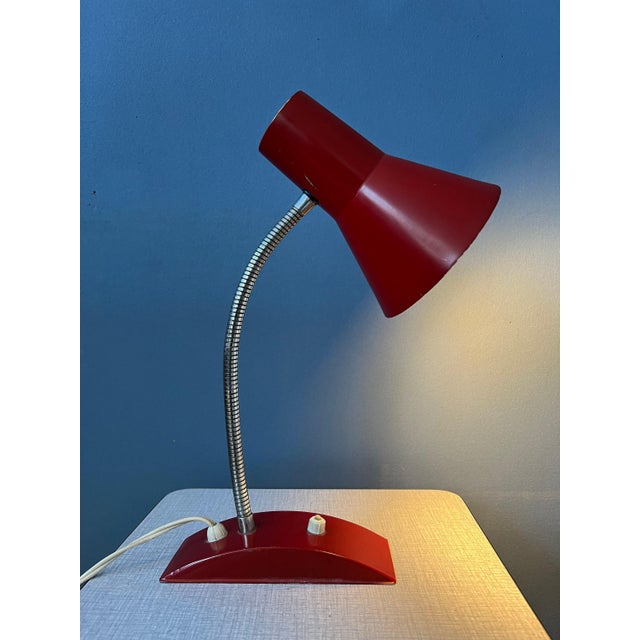 Red space age table lamp with flexible metal arm. The arm and shade can be positioned in any way desirable. The lamp is...