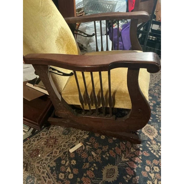 A Morris-style rocking chair with a dark wood frame, slatted sides, a pull-out footrest and gold velvet cushions. Details:...
