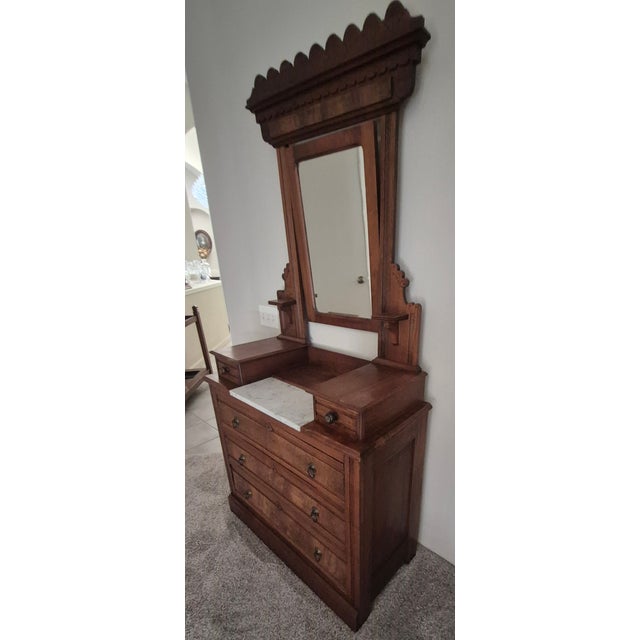 This antique Victorian Eastlake Burled dresser features a swivel mirror, five dovetailed drawers, brass hardware, and a...