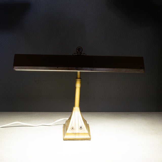 ABOUT An antique desk lamp featuring a bronze finish, a tilting adjustable rectangular hood shade, and a heavy base....