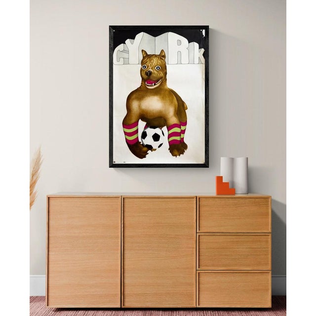 The Piece This charming vintage poster features a whimsical illustration of a brown dog, resembling a boxer, posing with a...