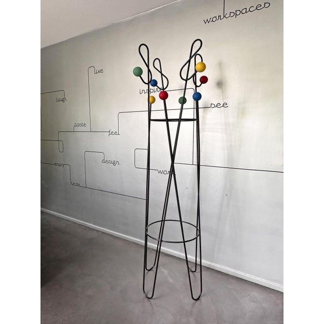 An iconic example of French Mid-Century design, featuring a black lacquered steel wire structure adorned with brightly...