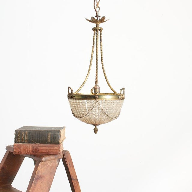 A beautiful antique empire french brass crystal beaded basket chandelier. The light has fabulous graduating cut glass...