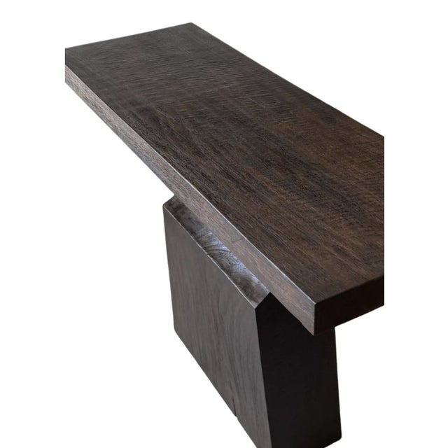 Crafted by skilled artisans on the island of Bali, this sculptural console table is hewn from solid mango wood and...
