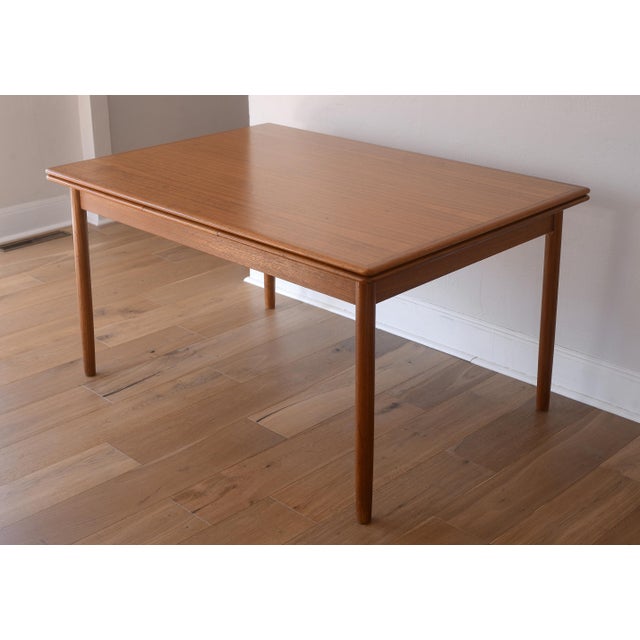 Desirable vintage Danish teak dining table in the style of Kurt Ostervig. This table has two 21" leaves that are hidden...