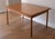Desirable vintage Danish teak dining table in the style of Kurt Ostervig. This table has two 21" leaves that are hidden...