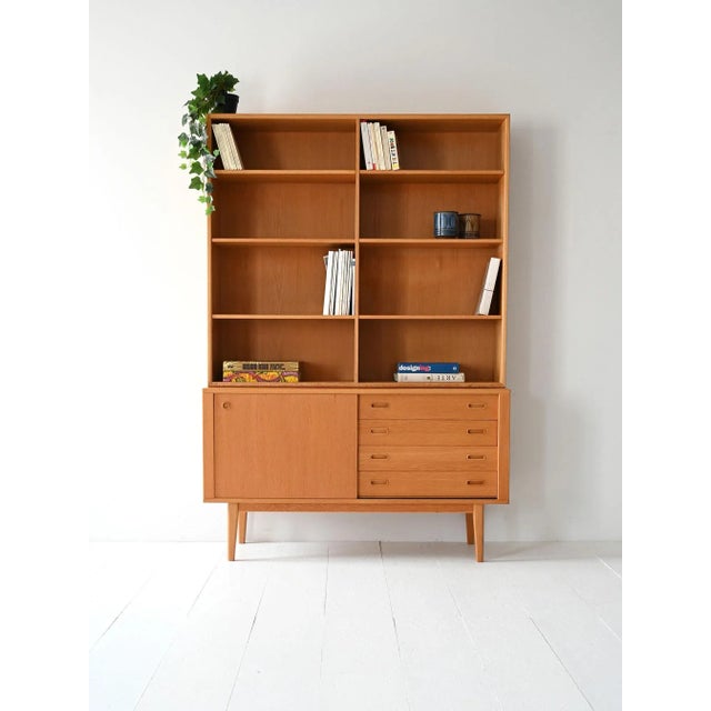 1960s bookcase with open shelves, drawers, and a storage compartment. Linear structure and light proportions typical of...