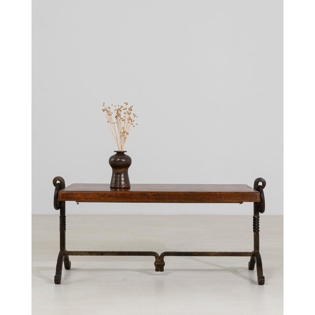 A bold Brutalist coffee table defined by its sculptural wrought iron base and strong geometric presence. The raw,...