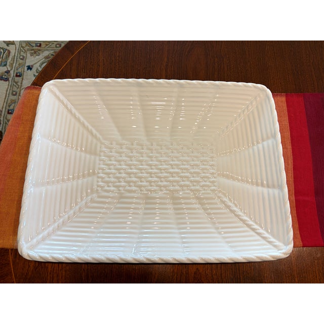 Offering a white ceramic rectangular serving dish or platter with a basketweave center and ribbed or fluted sides, closely...