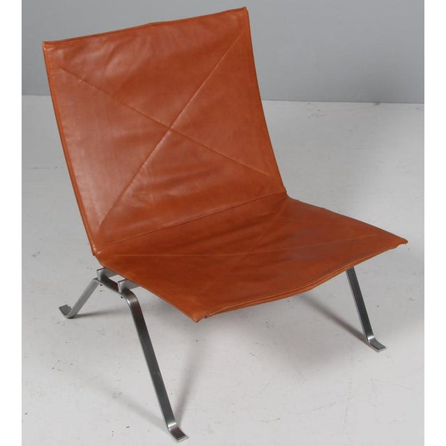 Poul Kjærholm lounge chair in patinated tan leather. Frame of brushed steel. Model PK22, made by Fritz Hansen. This piece...