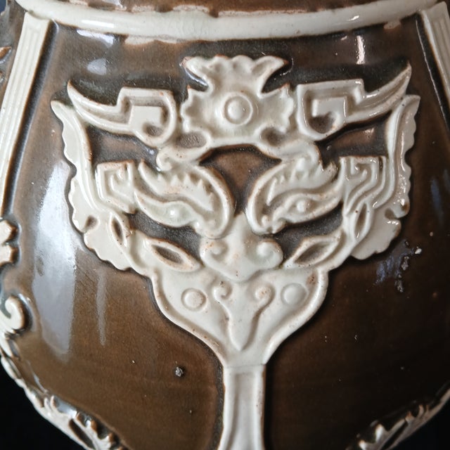 This is a very impressive ceramic vase. 19" tall and 9" wide, a soft brown glaze with raised white neoclassical designs...