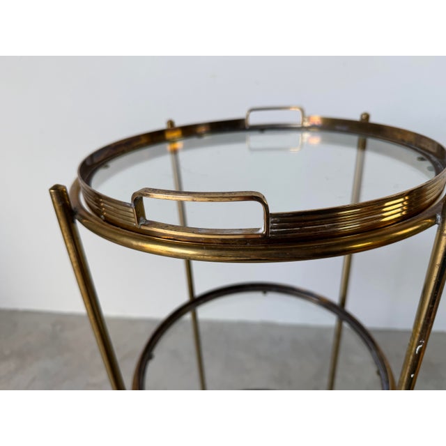 Elegant 1970s Maison Jansen Style Italian Hollywood Regency bar cart featuring a polished brass frame with three circular...