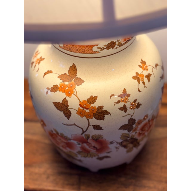 A charming mid‑century floral ceramic table lamp featuring a hand‑painted botanical motif and a carved soapstone collar,...