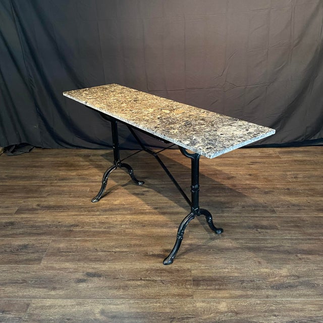 Elegant French bistro table featuring a long, narrow lovely early marble top raised on a classic Provencal slender black...
