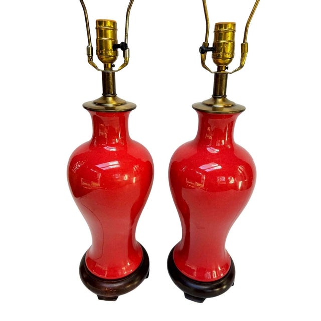 Elegant pair of vintage ceramic table lamps in a rich oxblood red glaze with subtle tonal depth. The elongated vase form...