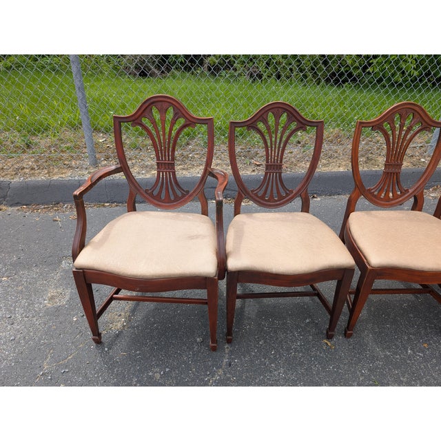 Elevate your dining space with this exceptional set of four vintage Drexel dining chairs in the classic Hepplewhite style....