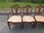 Elevate your dining space with this exceptional set of four vintage Drexel dining chairs in the classic Hepplewhite style....