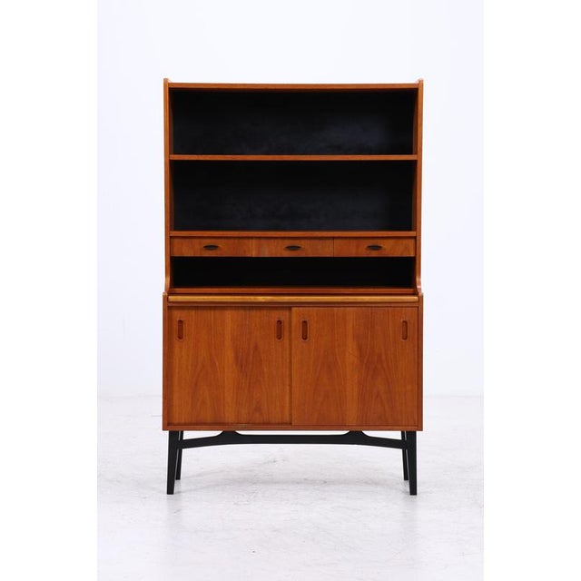 Vintage teak shelving unit with integrated secretary desk and ample storage space. The upper section features two open...