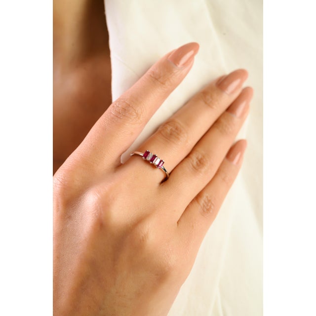 This elegant three-stone ring features three vibrant baguette-cut natural rubies totaling 0.38 carats, set in 14K white...