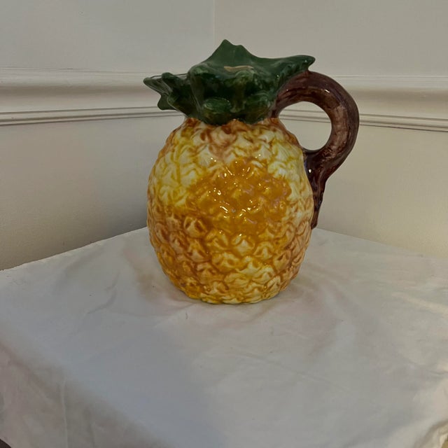 Hand made Italian majolica pineapple pitcher featuring green leaf spout and brown stem handle. Appears to be in display...