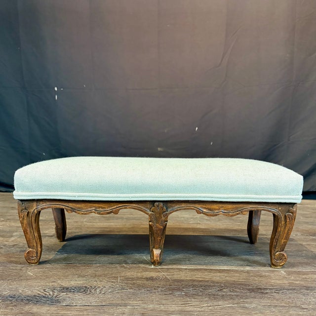 Elegant French carved walnut footstool featuring a shaped apron with finely carved shell and scroll detailing, raised on...