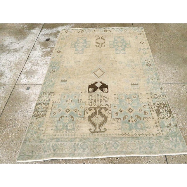 This mid-20th-century Persian Afshar throw rug presents a softly geometric composition in ivory, pale beige, muted aqua,...