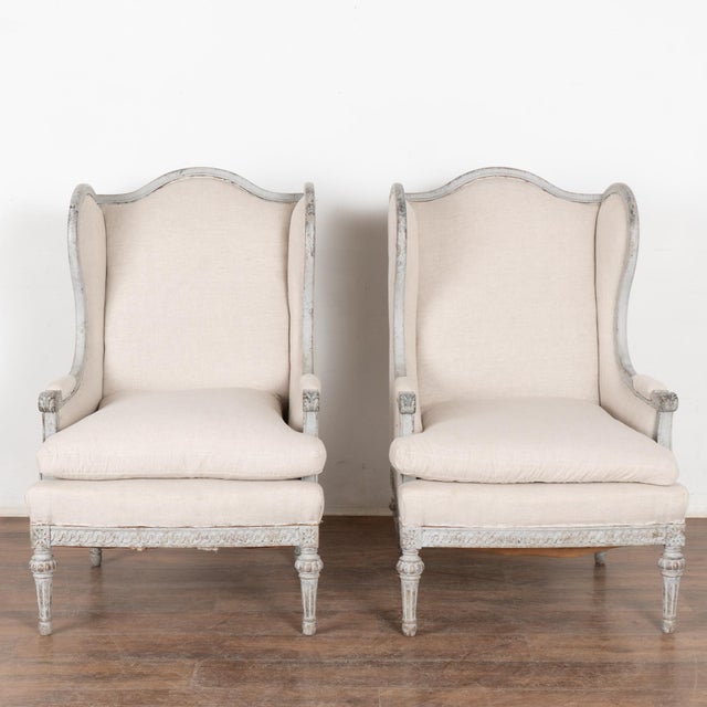 Graceful with a romantic air, this pair of Gustavian style wingback armchairs have delicate carving along the skirt skirt...