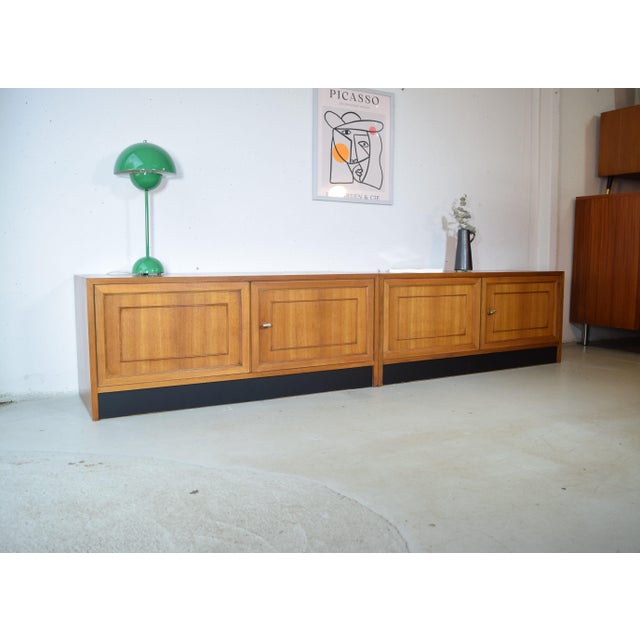 This is a modular walnut sideboard from the 1960s. The sideboard features a slim, floor-to-ceiling design with four doors....