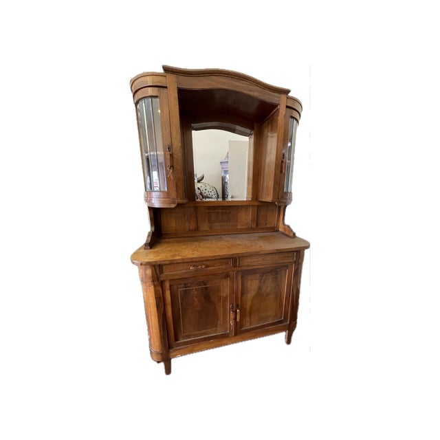 This elegant walnut buffet features bowed glass display cabinets, a carved mirrored back, and flowing curved lines...