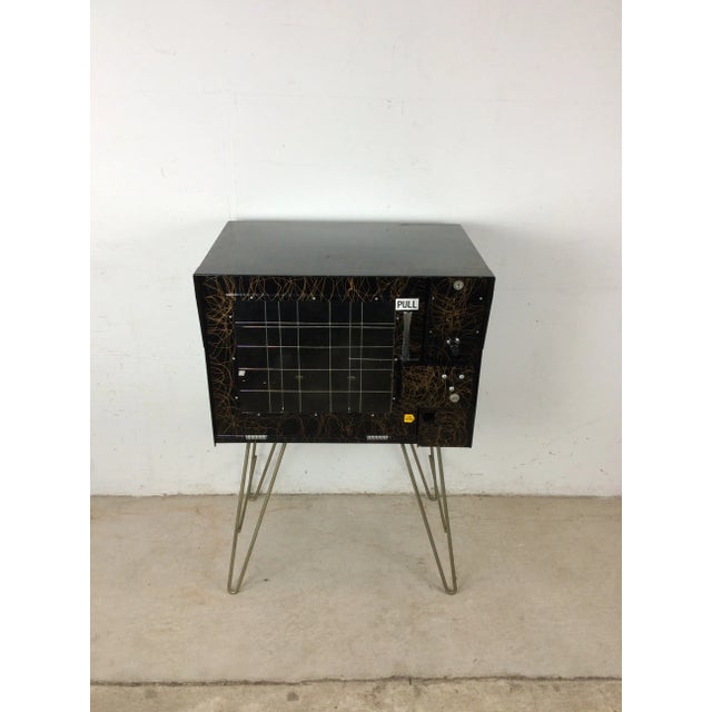 This mid century modern “Sho Rack” newspaper vending machine features metal frame construction, black painted design with...