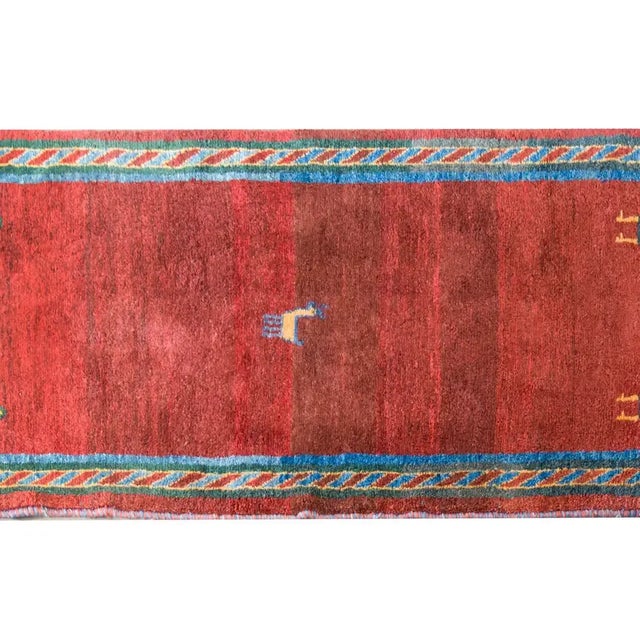 A remarkable late 20th century Persian Gabbeh rug with a wonderful abrash crimson field woven with a small goat in the...