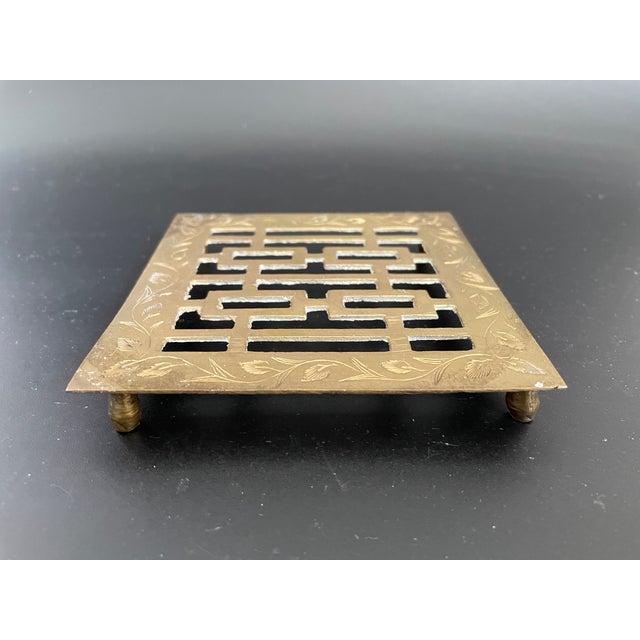 This vintage brass trivet features the Chinese Double Happiness symbol at the center, accented with engraved foliage...