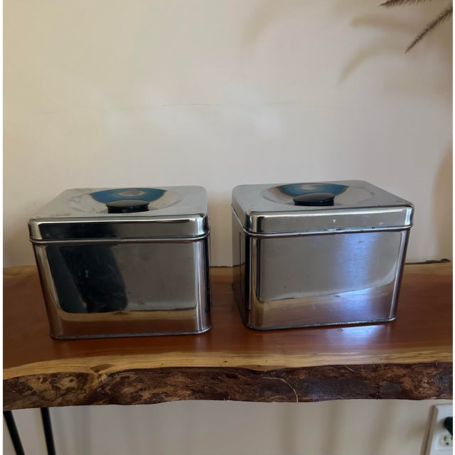 Stylish vintage pair of chrome kitchen storage canisters with streamlined mid-century styling. The canisters feature...