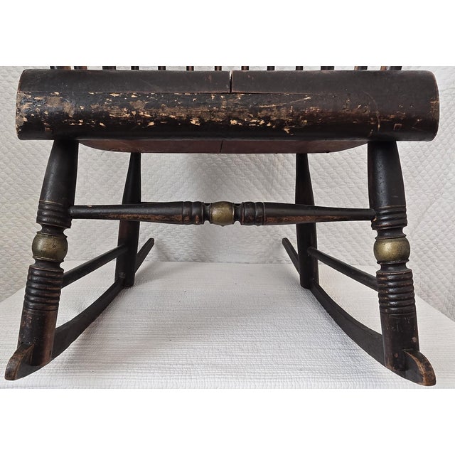 This antique Windsor rocking chair features a classic sack-back form with a high spindle back, shaped crest rail, and...