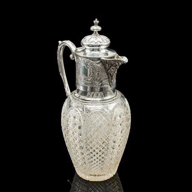 This is an antique dessert wine jug. An English, cut glass and silver plated serving ewer, dating to the late Victorian...
