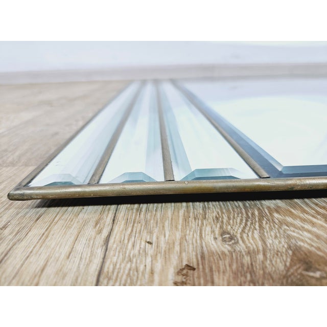 The decorative wall mirror has a unique, fan-shaped shape with a rounded top edge. It consists of one large main panel,...